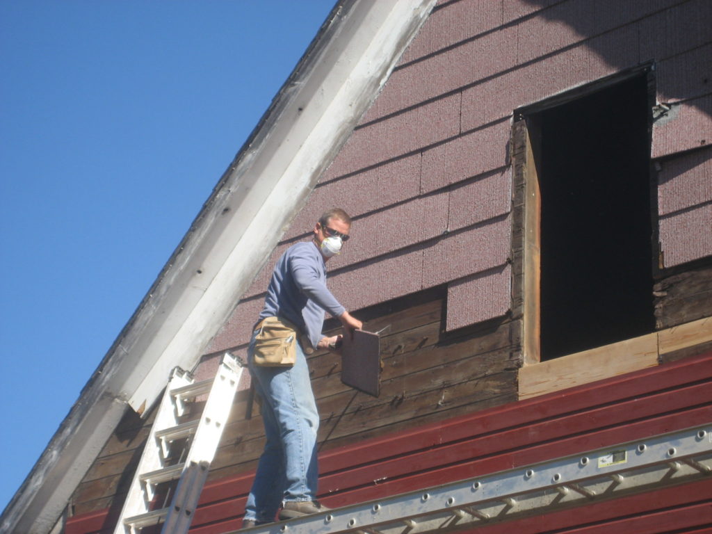 Removal_of_old_pink_siding_off_corn_crib_to_install_old_cypress_wood_to